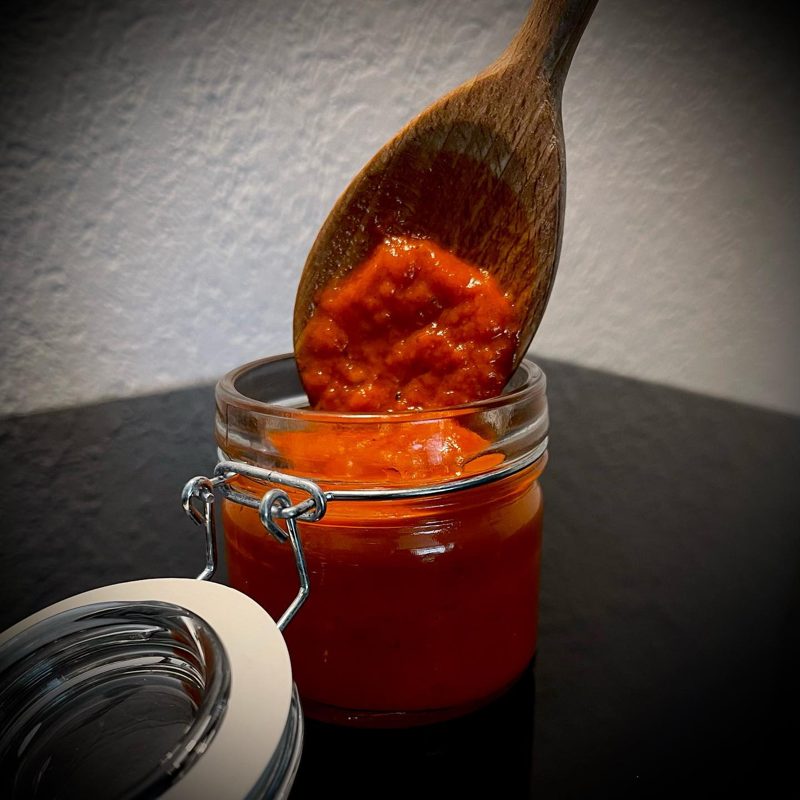 Holzlöffel mit Sauce über einem offenen Glas